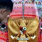 Seorang pria memegang burung Garuda Pancasila di mobil bercorak Ulos Mandailing yang akan digunakan acara ngunduh mantu Kahiyang-Bobby di Medan, Senin (20/11). (Liputan6.com/JohanTallo)