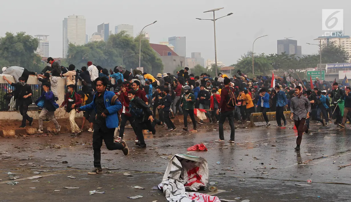 Mahasiswa berlarian saat polisi menembakkan gas air mata dan water cannon dalam demonstrasi menolak pengesahan RUU KUHP dan revisi UU KPK di depan Gedung DPR, Jakarta, Selasa (24/9/2019). Polisi menghalau mahasiswa yang berusaha masuk ke area Gedung DPR. (Liputan6.com/JohanTallo)