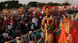 Sepasang pengantin berjalan bersama saat nikah massal di Surat, India, Minggu (23/12). Sebanyak 261 pasangan mengikuti acara nikah massal kali ini. (AP/Ajit Solanki)