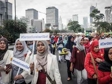 Peserta ISMAFARSI (Ikatan Senat Mahasiswa Farmasi Seluruh Indonesia) memperingati Hari Apoteker Sedunia di kawasan Car Free Day, Jakarta, Minggu (25/9). Mereka mengajak masyarakat cerdas menggunakan obat, termasuk DaGuSiBu. (Liputan6.com/Faizal Fanani)