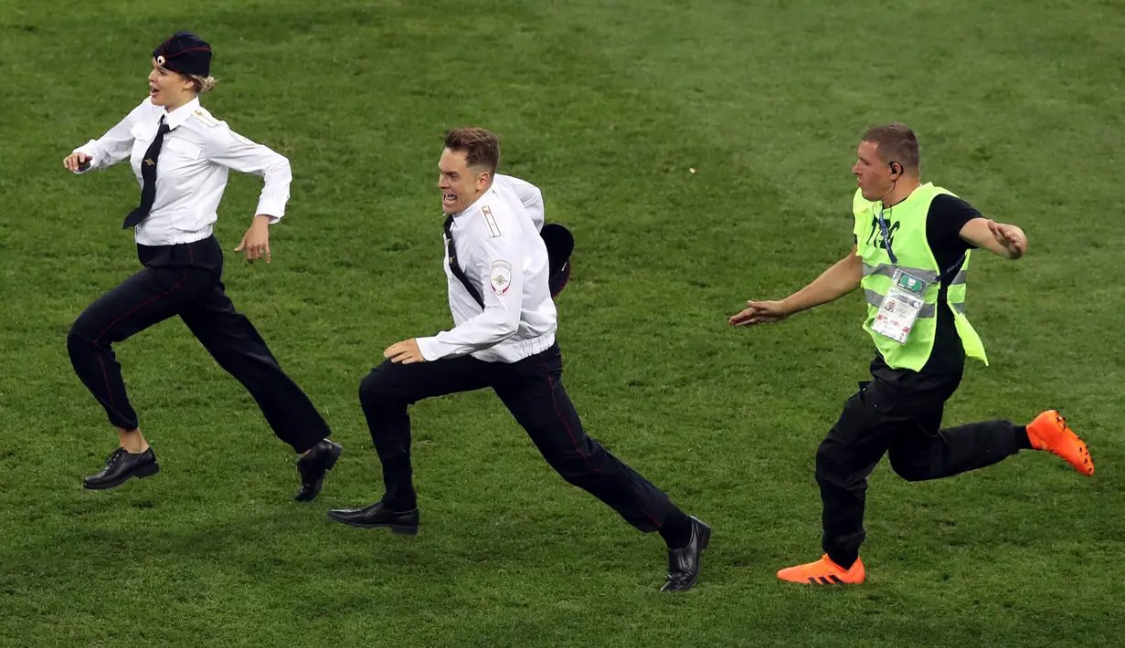 Petugas mengejar dua penyusup yang masuk ke lapangan dalam laga final Piala Dunia 2018 antara Prancis dan Kroasia di Luzhniki Stadium, Minggu (15/7). Pertandingan sempat dihentikan sebelum para penyusup ditangkap oleh petugas. (AP/Thanassis Stavrakis)