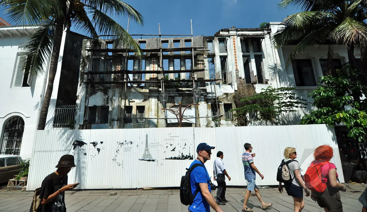 Warga melintas di depan bangunan rusak yang akan direvitalisasi di kawasan Kota Tua, Jakarta, Rabu (18/3/2015). Menteri Pariwisata telah mengeluarkan Keputusan Menteri yang menetapkan Kota Tua sebagai destinasi utama wisata. (Liputan6.com/Faizal Fanani)