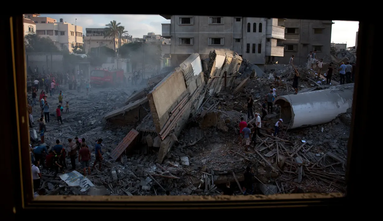 Warga melihat puing-puing bangunan yang hancur akibat serangan udara Israel di Kota Gaza, Palestina, (9/8). Tentara Israel kembali membombardir Gaza sebagai aksi balasan terhadap serangan militan Hamas. (AP Photo/Khalil Hamra)