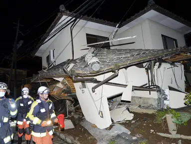 Petugas pemadam kebakaran memeriksa sebuah rumah yang runtuh setelah gempa bumi di kota Mashiki, Prefektur Kumamoto, Jepang selatan , Jumat (15/4). Gempa berkekuatan 6,4 SR itu menewaskan sembilan orang dan 760 lainnya terluka. (REUTERS/Kyodo)