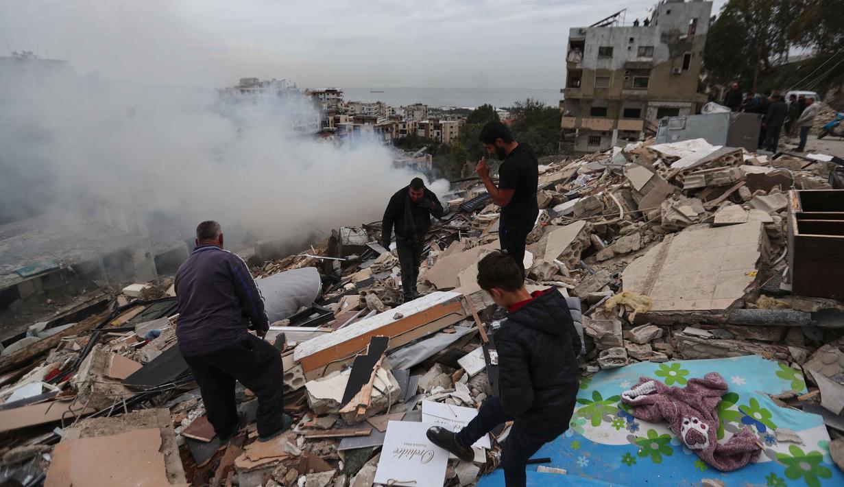 Serangan yang dilancarkan pada Rabu 21 Januari 2026 dilaporkan menewaskan sedikitnya dua orang dan melukai puluhan lainnya. Tampak dalam foto, asap mengepul saat orang-orang memeriksa bangunan yang hancur akibat serangan Israel di desa Qennarit, Lebanon selatan, Kamis 22 Januari 2026. (AP Photo/Mohammed Zaatari)