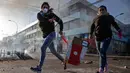 Penjarah melambaikan tanda 'V' ketika berlari selama protes di Valparaiso, Chile, Minggu (20/10/2019). Bentrokan pecah di Santiago setelah dua orang tewas ketika sebuah supermarket dibakar ketika protes terhadap kondisi ekonomi dan ketidaksetaraan sosial. (JAVIER TORRES/AFP)