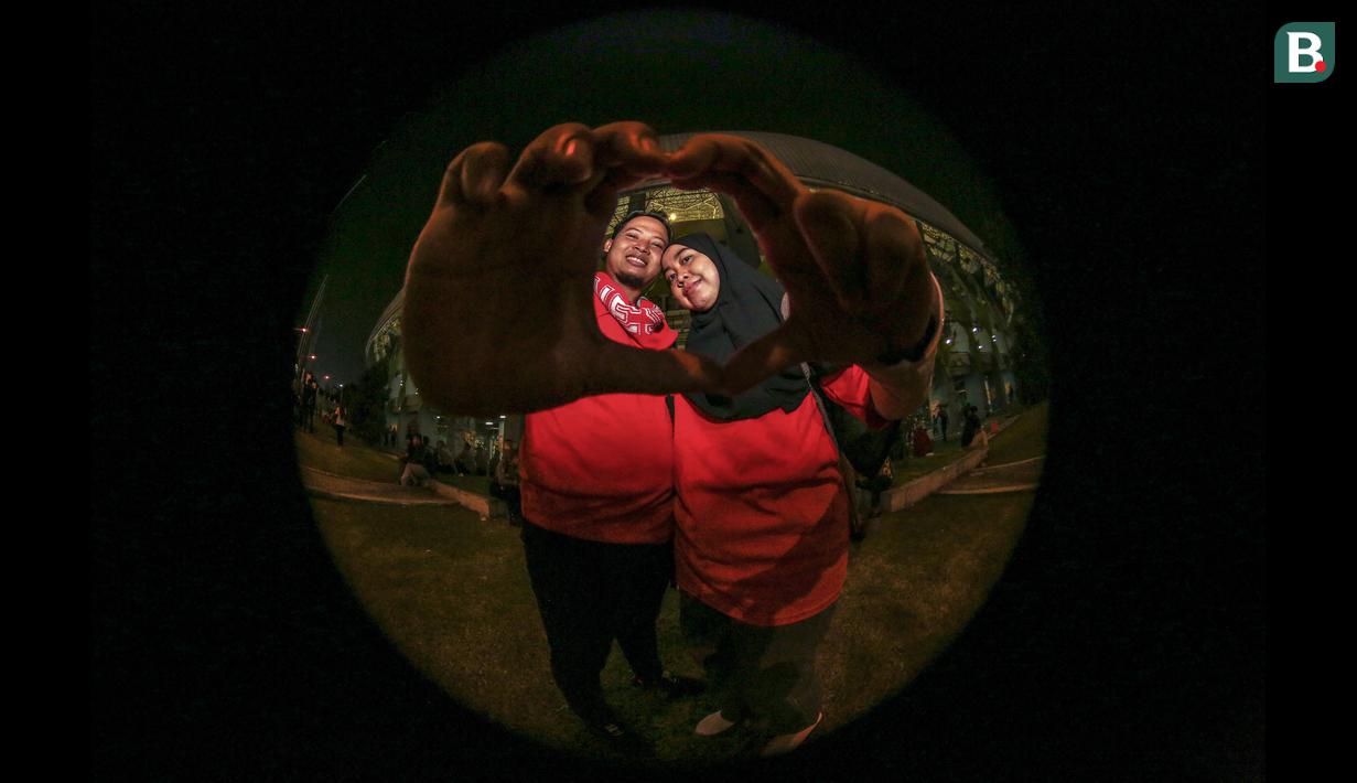 M Tarmo Wijaya (27) dan Ririn A (27) merupakan pasangan suami istri yang datang langsung untuk menyaksikan Timnas Indonesia U-19 di Stadion Patriot Candrabhaga. Beginilah tanggapan mereka soal Timnas Indonesia U-19 di ajang Piala AFF U-19 2022: "Timnas Indonesia U-19 asuhan Indra Safri itu sudah bagus. Namun, setelah dilepas, performanya agak menurun. Nah, setelah dipegang oleh Shin Tae-yong sudah menunjukkan perkembangan. Kelemahan untuk saat ini adalah lini belakang yang belum percaya diri." (Bola.com/Bagaskara Lazuardi)