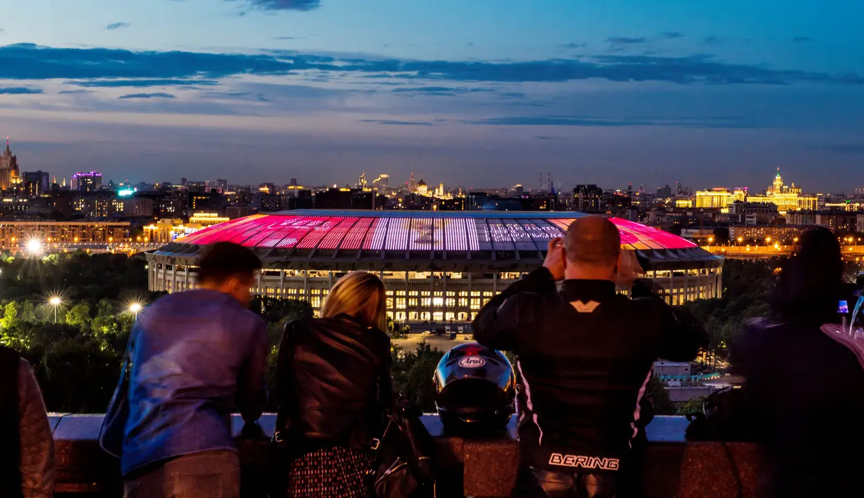 Sejumlah warga menikmati suasana malam dengan latar belakang Stadion Luzhniki, Moscow, Kamis,(6/7/2017). Stadion Luzhniki akan menjadi stadion untuk pembukaan dan penutupan Piala Dunia 2018 Rusia. (AFP/Mladen Antonov)