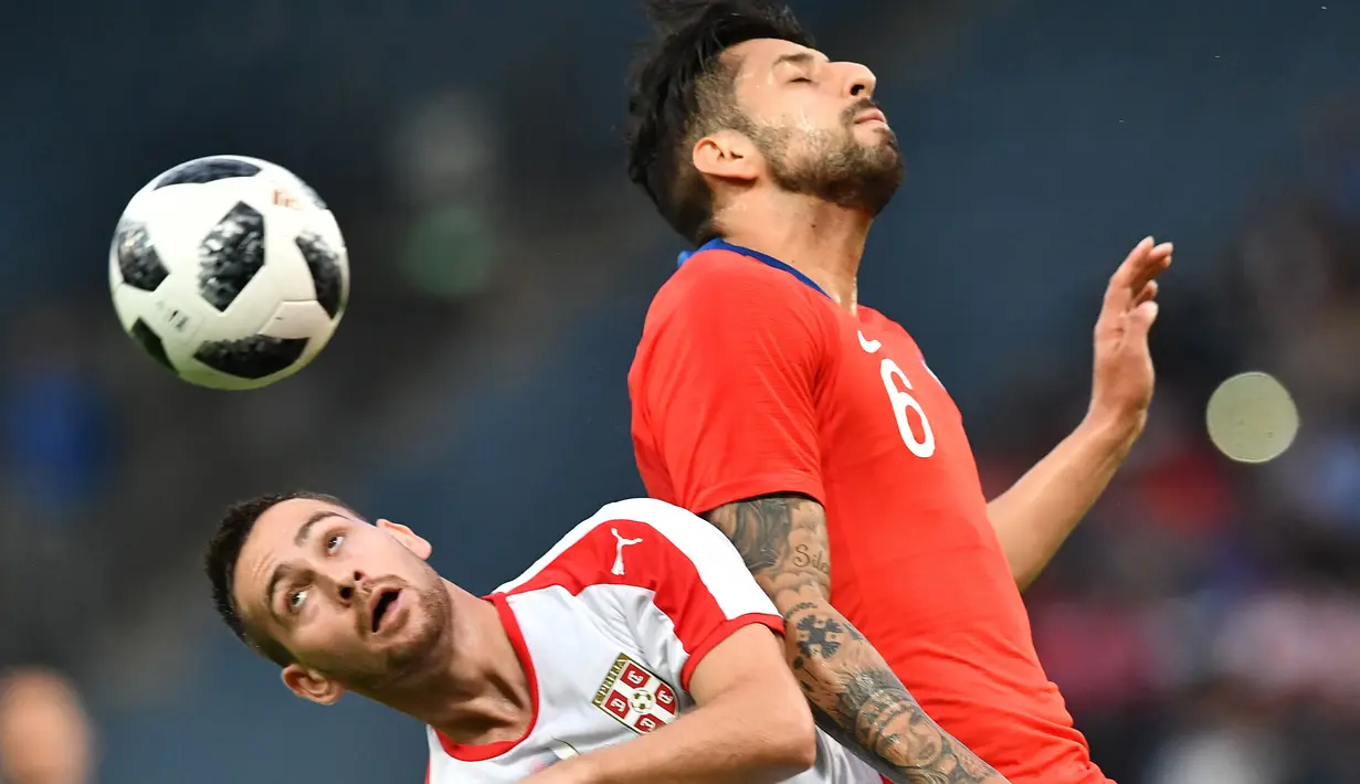 Pemain Serbia, Andrija Zivkovic (kiri) berusaha menghalau bola sundulan pemain Chili, Gillermo Maripan pada laga uji coba di Merkur Arena, Graz, Austria, (4/6/2018). Serbia kalah dari Chili 0-1. (AFP/Joe Klamar)