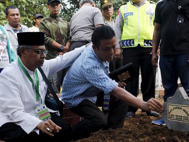 Seorang ulama (kiri) dan Iwan Setiawan, saudara laki-laki terpidana mati Zainal Abidin, saat prosesi pemakaman di TPU di Cilacap, Jateng, Rabu (29/4). Zainal satu-satunya terpidana mati asal Indonesia yang dieksekusi dini hari ini. (REUTERS/Beawiharta)