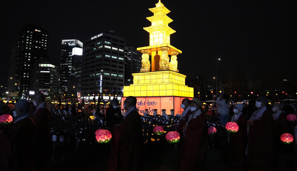 Umat Buddha Korea Selatan mengenakan masker membawa lentera lotus berwarna-warni selama upacara pencahayaan untuk merayakan ulang tahun Buddha yang akan datang pada 8 Mei, di Seoul, Korea Selatan (5/4/2022). (AP Photo/Lee Jin-man)