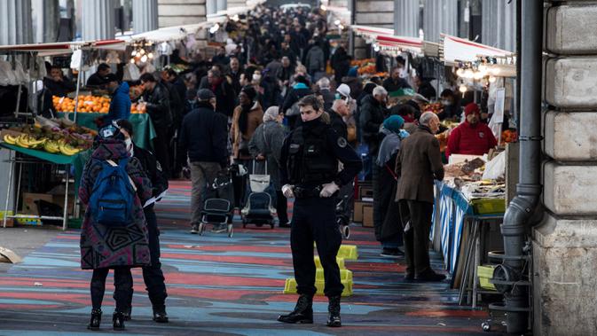 Polisi berjaga saat warga berbelanja ketika lockdown di Barbes Market, Paris, Prancis, Rabu (18/3/2020). Prancis menjadi negara dengan kasus virus corona COVID-19 terbanyak ketujuh di dunia. (JOEL SAGET/AFP)