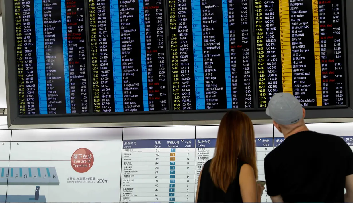 Calon penumpang pesawat mengamati jadwal penerbangan di bandara Hong Kong, Rabu (14/8/2019). Bandara Hong Kong kembali membuka penerbangan keberangkatan pada Rabu pagi setelah sempat lumpuh selama dua hari akibat demonstran menduduki salah satu bandara tersibuk di dunia tersebut. (AP/Vincent Thian)