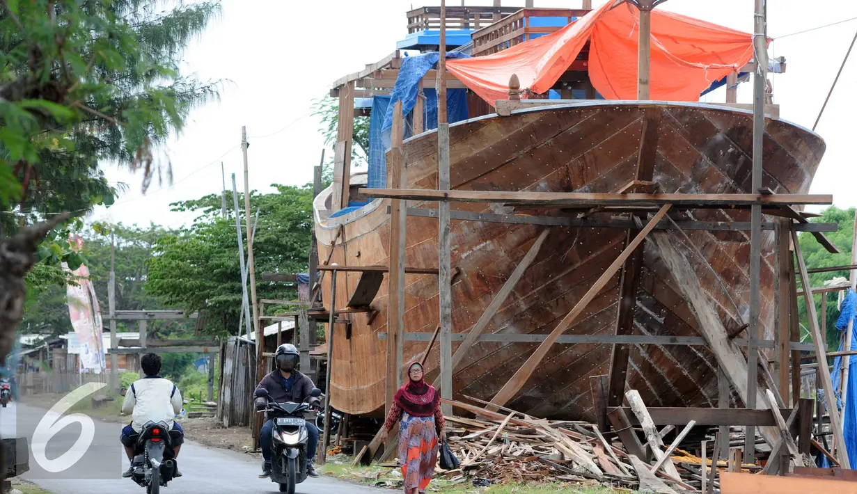 Warga melintas di area pembuatan perahu di Balongan, Indramayu, Jawa Barat, Jumat (15/1/2016). Dibutuhkan waktu selama delapan bulan untuk menyelesaikan satu unit perahu yang dijual seharga Rp.4 miliar - Rp.5 miliar tersebut. (Liputan6.com/Helmi Afandi)