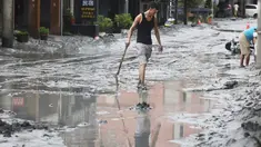 Seorang warga berjalan dengan sekop di sepanjang jalan yang tertutup lumpur di Hualien pada 24 September 2025, setelah bendungan danau jebol akibat terjangan Topan Super Ragasa. (I-Hwa Cheng/AFP)