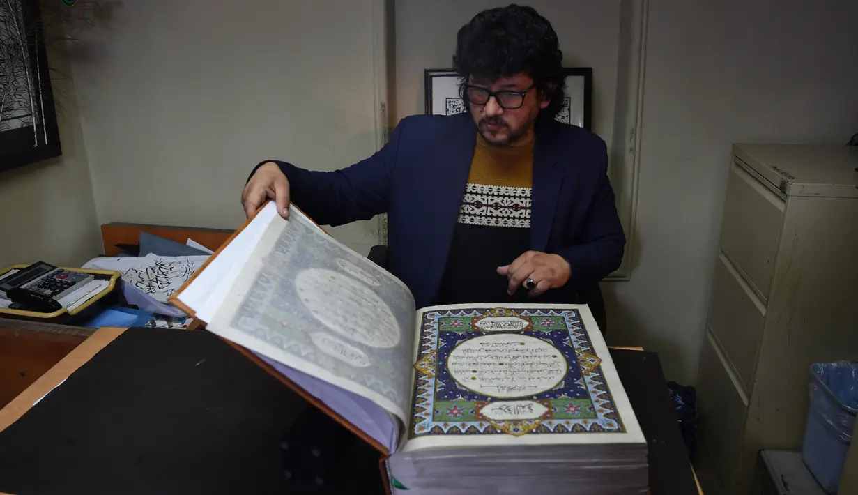 Seorang seniman Afghanistan, Mohammad Tamim Sahibzada menunjukkan Alquran buatan tangan di Mourad Khani, Kabul, Afghanistan (19/4). (AFP/Wakil Kohsar)