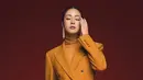 Kang Sora terlihat menawan di photoshoot ini. Ia mengenakan setelan jas dan celana panjang berwarna oranye, dipadu padankan dengan turtleneck yang serasi. [Foto: Instagram/reveramess_]