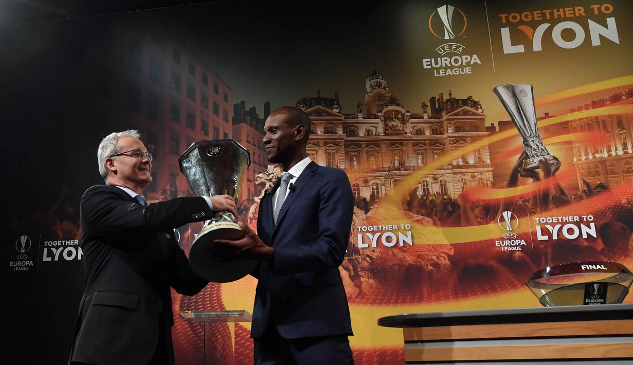 Mantan pesepak bola Prancis, Eric Abidal, menerima trofi saat undian semifinal Liga Europa di Nyon, Swiss, Jumat (13/4/2018). Arsenal akan melawan Atletico Madrid, Marseille melawan Salzburg. (AFP/Fabrice Coffrini)