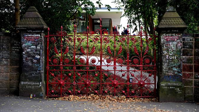 Graffiti digambarkan di gerbang Strawberry Field yang baru dibuka untuk umum di Liverpool, Rabu (18/9/2019). Strawberry Field adalah nama sebuah panti Salvation Army di sekitar sudut rumah masa kecil John Lennon yang menjadi populer dan kini dibuka untuk umum usai 70 tahun ditutup. (Paul ELLIS/AFP)