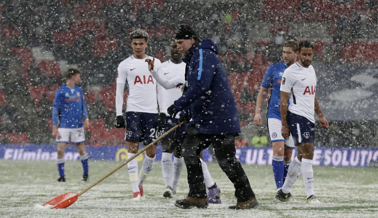 Seorang petugas membersikan salju dari alapangan saat babak kelima Piala FA antara Tottenham Hotspur melawan Rochdale di Wembley stadium, London, (28/2/2018). Tottenham menang 6-1. (AP/Matt Dunham)