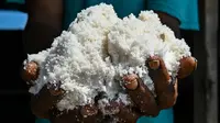 Seorang petani menunjukkan garam yang sedang diproses dengan cara tradisional di sebuah tambak di Lamnga, pinggiran Banda Aceh, Aceh, Selasa (7/3/2023). Kebutuhan garam industri jauh lebih besar daripada kebutuhan konsumsi rumah tangga. (CHAIDEER MAHYUDDIN/AFP)