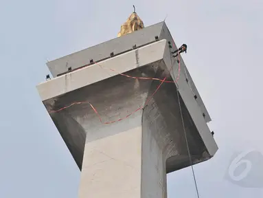 Monas mulai 'dimandikan' pada Kamis (08/05/14). Dengan terikat tali, seorang teknisi tampak membersihkan bagian atas tugu setinggi 132 meter (Liputan6.com/Johan Tallo)  