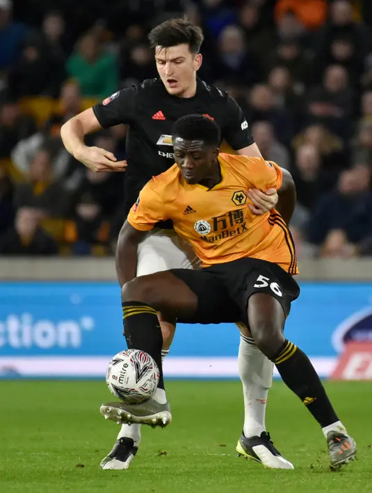 Pemain Wolverhampton Wanderers, Benny Ashley-Seal berebut bola dengan bek Manchester United, Harry Maguire pada babak ketiga Piala FA di Molineux, Sabtu (4/1/2020). Wolverhampton dan MU dipaksa untuk melakukan laga ulangan di Old Trafford usai bermain imbang tanpa gol. (AP/Rui Vieira)