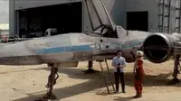 J.J. Abrams yang sedang berdiri di depan tangga pesawat, dihampiri oleh pilot yang mengenakan kostum Star Wars Episode VII.