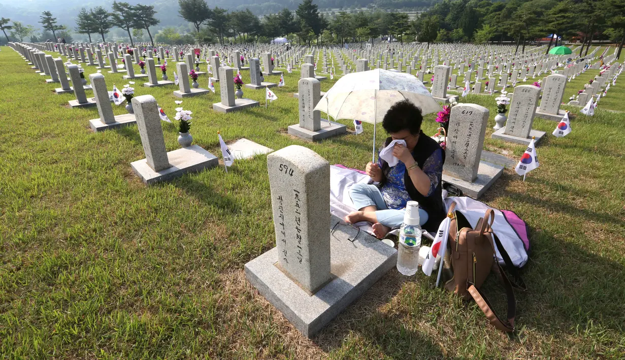 Warga Korea Selatan,Oh Myung-Soon menangis di depan batu nisan saudaranya yang meninggal selama Perang Korea di pemakaman nasional, Seoul, Korea Selatan, Rabu (6/6). Kegiatan ini dilakukan dalam Memorial Day. (AP Photo/Ahn Young-joon)