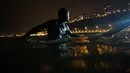 Ernesto Benavides menunggu datangnya ombak dari Samudra Pasifik saat akan berselancar di pantai La Pampilla, ibu kota Peru, Lima, 8 Maret 2017. Sekelompok peselancar hardcore memilih bermain selancar pada malam hari. (AP Photo/Rodrigo Abd)