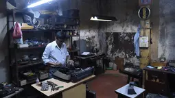Teknisi mesin tik, Anand Savarkar memperbaiki mesin tik di bengkelnya di Mumbai, India (6/7). Mesin tik di India kini mulai ditinggalkan, karena terasa sudah ketinggalan zaman di era komputer dan Internet. (AFP Photo/Indranil Mukherjee)