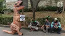 Sejumlah aktivis dari People for the Ethical Treatment of Animals (PETA) menggunakan kostum dinosaurus sambil membawa poster di kawasan Dukuh Atas, Jakarta, Selasa (24/10/2023). (Liputan6.com/Angga Yuniar)