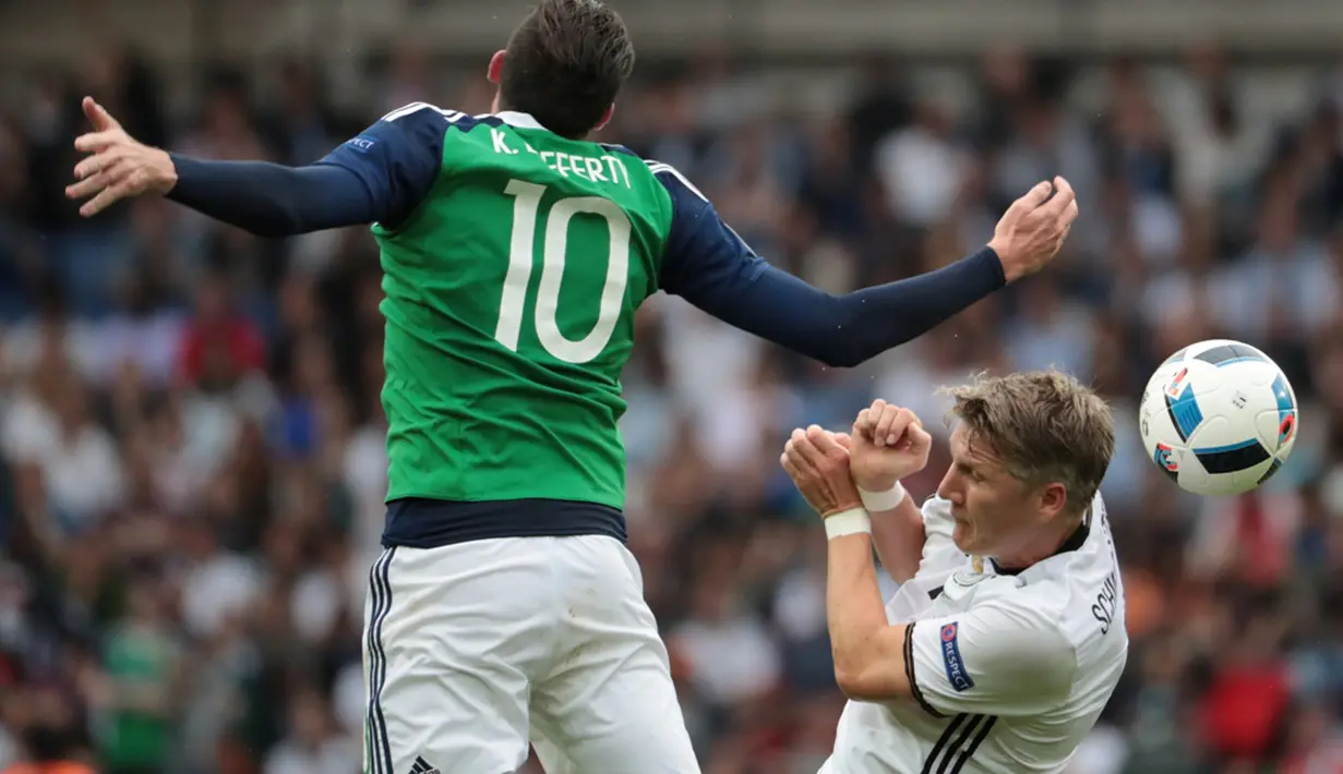 Pemain Jerman, Bastian Schweinsteiger, duel dengan pemain Irlandia Utara, Kyle Lafferty, pada laga Grup C Piala Eropa 2016 di Parc des Princes, Paris, Selasa (21/6/2016). (AFP/Kenzo Tribouillard)