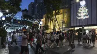 Pejalan kaki menyeberang jalan yang didekorasi dengan lampu Natal di distrik perbelanjaan Orchard road di Singapura, Selasa (8/12/2020). Mengusung tema Love This Christmas, acara tahun ini lebih sunyi karena aktivitas jalanan dibatasi di tengah pandemi Covid-19. (ROSLAN RAHMAN / AFP)