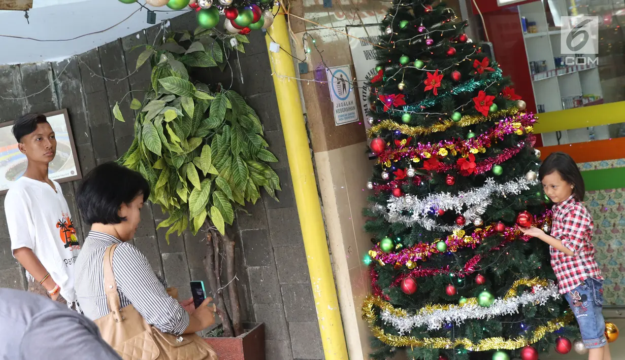 Seorang anak berfoto di dekat pohon Natal di Terowongan Penyebrangan Orang (TPO) Kota Tua, Jakarta, Jumat (21/12). Jelang perayaan Natal 2018, TPO Kota Tua dihiasi pernak-pernik. (Liputan6.com/Helmi Fithriansyah)