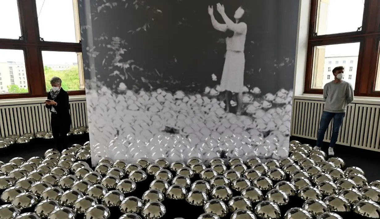 Pengunjung berjalan melewati ruangan dengan instalasi 'Narcissus Garden' karya seniman kontemporer Jepang Yayoi Kusama dalam pameran Yayoi Kusama: A Retrospective di Atrium Martin Gropius Bau, Berlin, Jerman, Selasa (19/5/2021). (John MACDOUGALL/AFP)