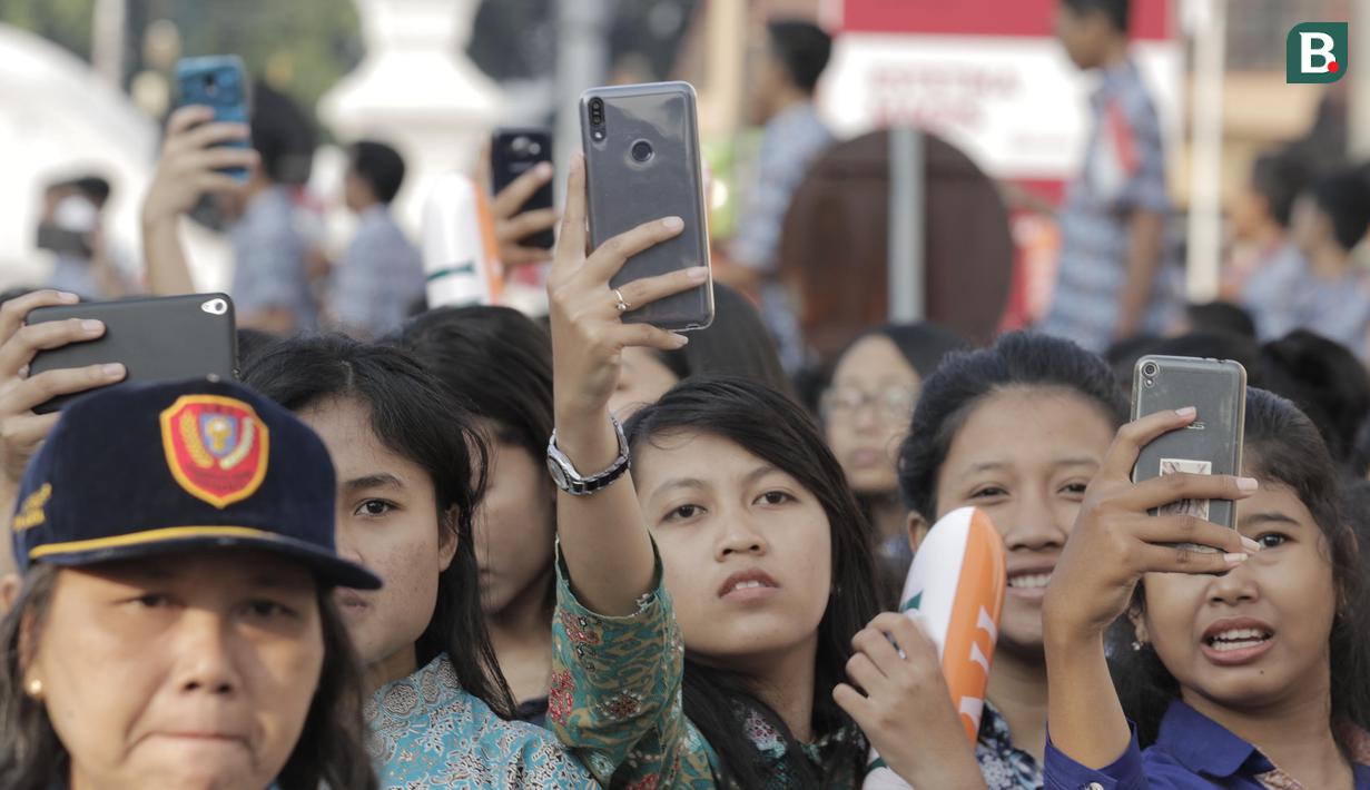 Sejumlah siswa mengabadikan momen kirab obor Asian Games 2018 di Pagelaran Keraton Yogyakarta, Kamis (19/7/2018). Total jarak kirab Obor di Yogya ini sepanjang 11,5 kilometer. (Bola.com/M Iqbal Ichsan)
