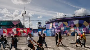 Pejalan kaki berjalan di dekat situs Paralimpiade Place de la Concorde yang ditutupi terpal "Paris 2024" menjelang ajang Paralimpiade 2024 di paris, Rabu (21/8/2024). (Dimitar DILKOFF / AFP)