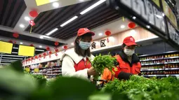 Relawan masyarakat Wang Shujia (kiri) dan rekannya membelikan sayur untuk warga lanjut usia di Hefei, Provinsi Anhui, China timur (5/3/2020). Wang Shujia, seorang mahasiswi, ambil bagian dalam tim relawan masyarakat di Hefei untuk membantu mencegah dan mengendalikan epidemi virus corona. (Xinhua/Liu