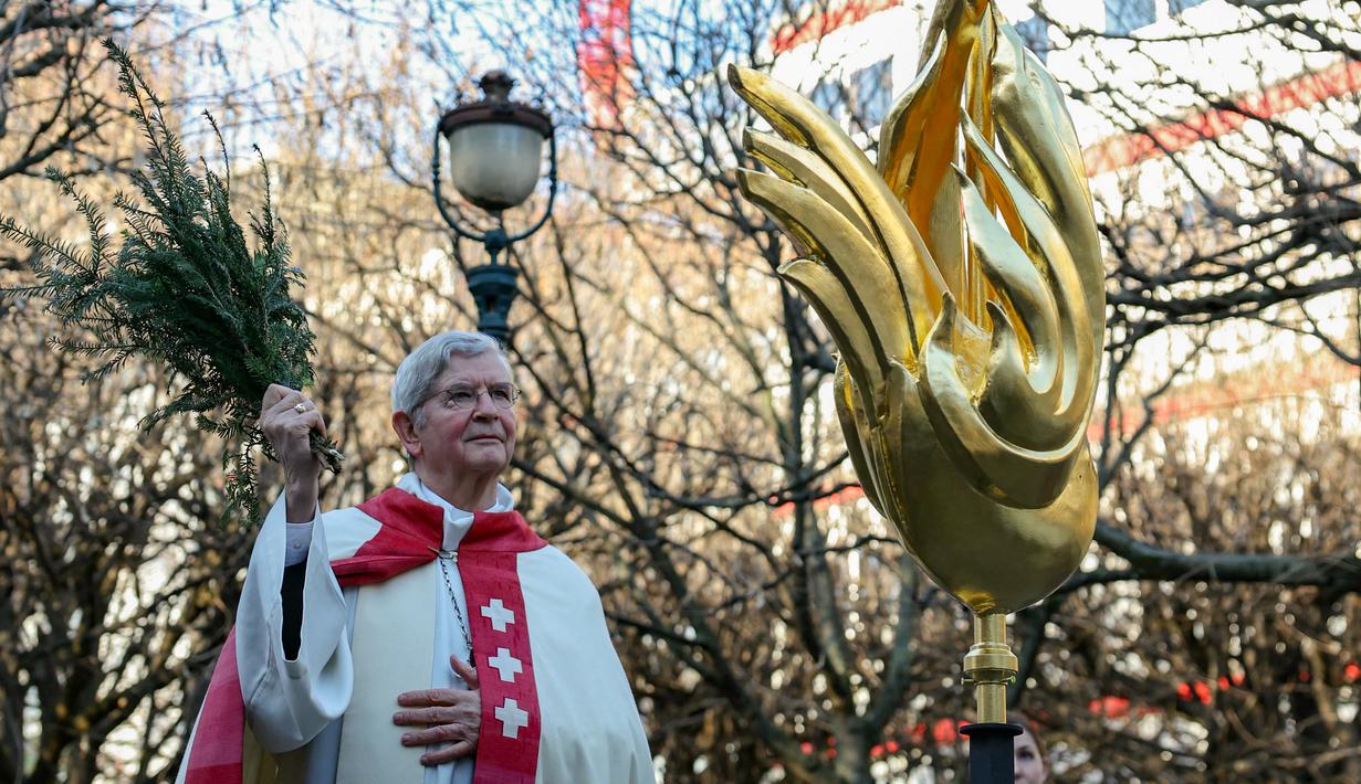 Uskup Agung Paris Laurent Ulrich memberkati ayam jantan itu dengan sayap emas seperti api sebelum diangkat ke tempatnya di puncak menara katedral setinggi 96 meter (315 kaki). (Thomas SAMSON / AFP)