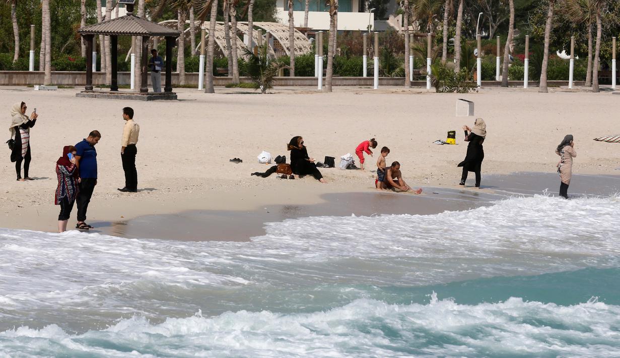 Turis bersantai di pinggir pantai, Pulau Kish di Iran, 1 November 2016. Pantai Kish yang terletak di kawasan pesisir Iran ini berjarak hanya 200 kilometer dari Dubai. (Atta Kenare/AFP)