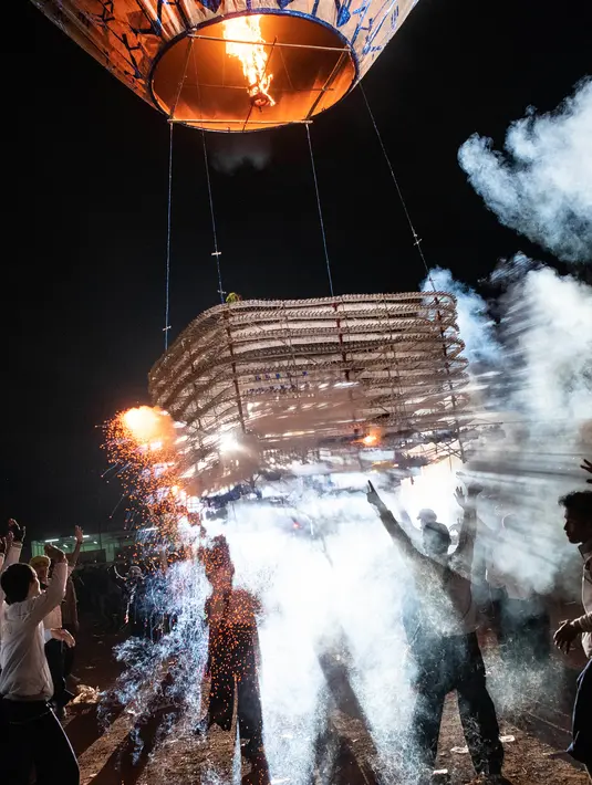 Peserta melepaskan balon udara yang membawa lentera kecil selama Festival Tazaungdaing di Taunggyi, Myanmar pada 14 November 2018. Perayaan festival ini digelar saat bulan purnama bersinar di langit malam Myanmar. (Ye Aung THU / AFP)