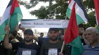 Warga Palestina di Kota Gaza pada 24 Juni 2019, mengibarkan bendera nasional dan memegang spanduk yang mengecam konferensi Perdamaian untuk Kemakmuran yang dipimpin AS di Bahrain. (MOHAMMED ABED / AFP)