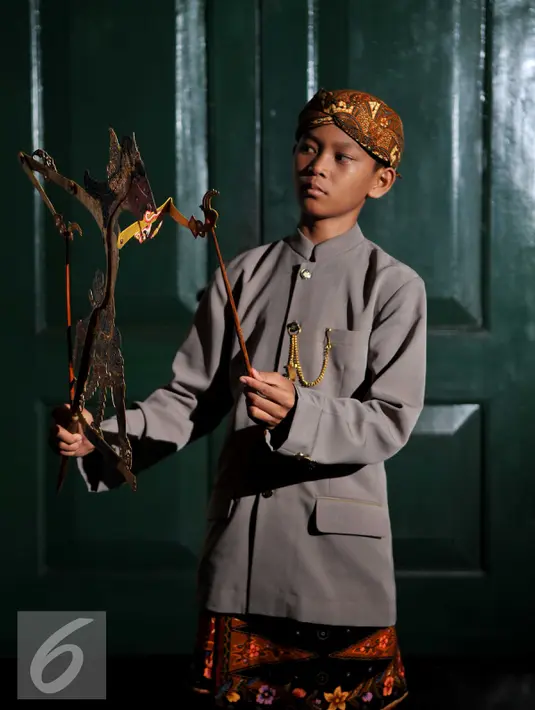 Seorang anak berpose dengan memegang sebuah wayang selama festival Dalang Bocah di Kawasan Kota Tua, Jakarta (20/11).  Festival akan berlangsung dari 20-22 November 2015. (Liputan6.com/Gempur M Surya)