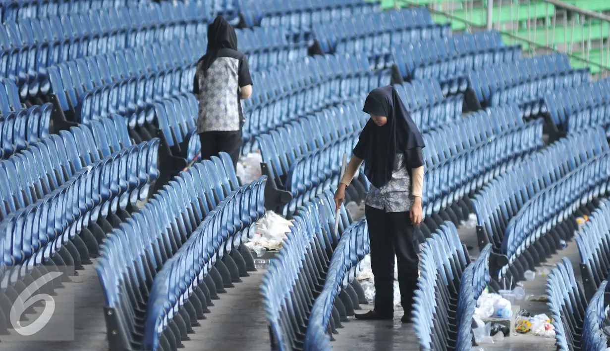 Petugas kebersihan membersihkan tumpukan sampah usai pertandingan final piala presiden di Stadion GBK, Jakarta (19/10/15). Pertandingan final tersebut dimenangkan oleh Persib Bandung 2-0. (Liputan6.com/Gempur M Surya).