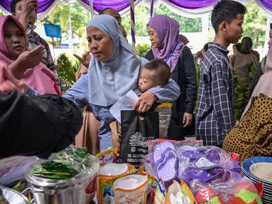 Masyarakat menerima barang-barang gratis seperti pakaian, bahan makanan pokok, dan perlengkapan rumah tangga yang disediakan oleh Asosiasi Organisasi Wanita (GOW) dan pemerintah daerah selama kegiatan aksi sosial tahunan di bulan Ramadan, Surabaya pada Senin 2 Maret 2026. Bersama Pemerintah Kota Surabaya, Jawa Timur, Gabungan Organisasi Wanita (GOW) aksi sosial tahunan, berupa peendistribusian berbagai barang bantuan kepada warga yang membutuhkan. (JUNI KRISWANTO/AFP)