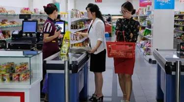 Dua wanita berada di kasir di supermarket di Pyongyang, Korea Utara (12/9). Banyak produk dalam negeri terlihat di rak-rak supermarket tersebut sebagai bagian dari upaya membangun ekonominya dan meningkatkan standar hidup nasional. (AP Photo/Kin Cheung)