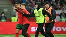 Pihak pengamanan menangkap seorang penyusup lapangan saat berusaha melakukan swafoto dengan pemain Portugal, Cristiano Ronaldo ketika laga lanjutan EUFA Nations League Polandia di National Stadium, Warsawa, Polandia, Minggu (13/10/2024) WIB. (AFP/Sergei Gapon)