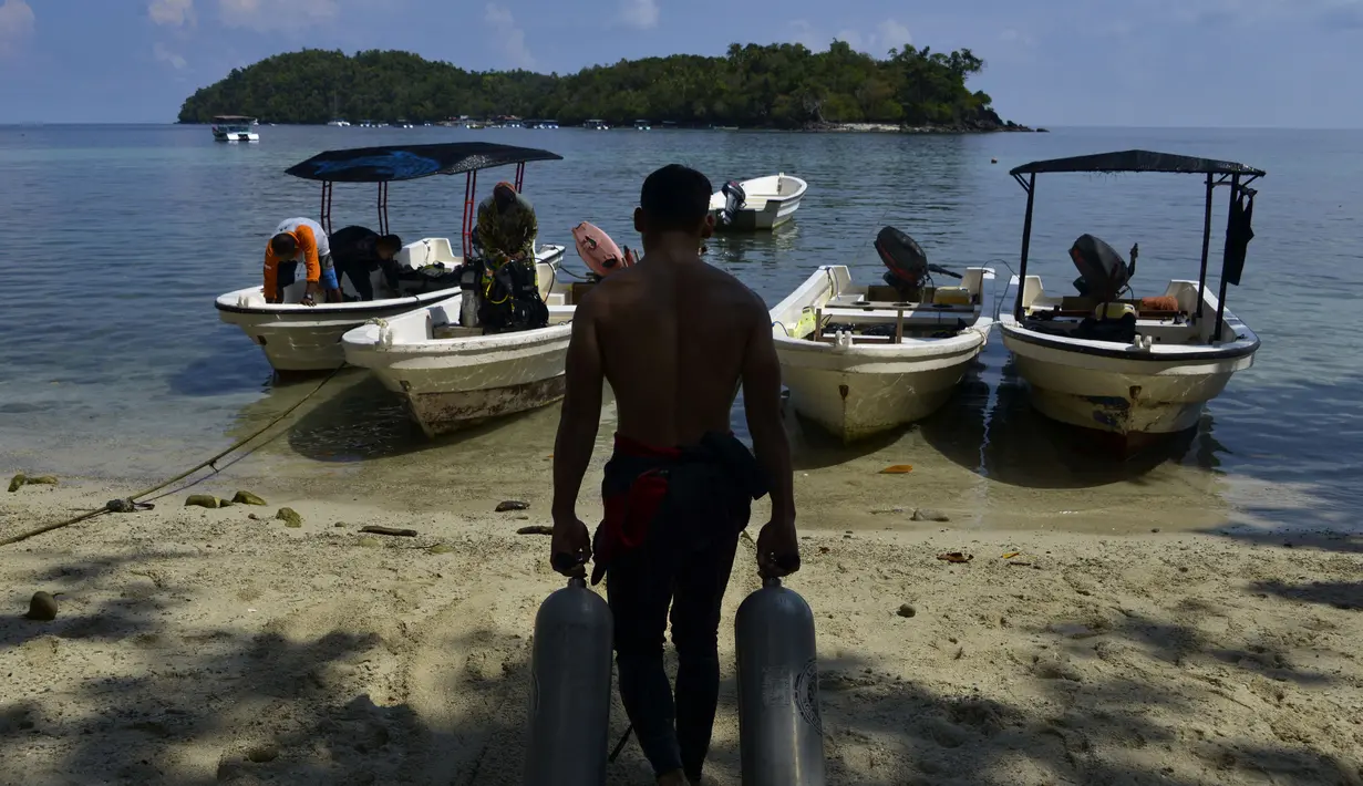 Pekerja membawa tabung oksigen isi ulang untuk scuba diving di Iboih, sebuah taman pantai dan pariwisata yang populer di seberang teluk dari Sabang di pulau Weh, provinsi Aceh (6/10/2019). Menyelam, mendaki gunung berapi dan resor pantai adalah daya tarik utama dari pulau ini. (AFP Photo/Chaideer Ma