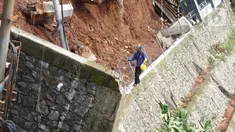 Petugas melintas di dekat turap yang hancur di Jalan Damai, Ciganjur, Jakarta Selatan, Minggu (11/10/2020). Hujan yang deras sejak Sabtu (10/10/2020) sore mengakibatkan kawasan tersebut mengalami banjir sekaligus longsor. (Liputan6.com/Immanuel Antonius)
